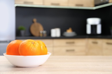 Photo of Fresh oranges on wooden table in kitchen. Space for text