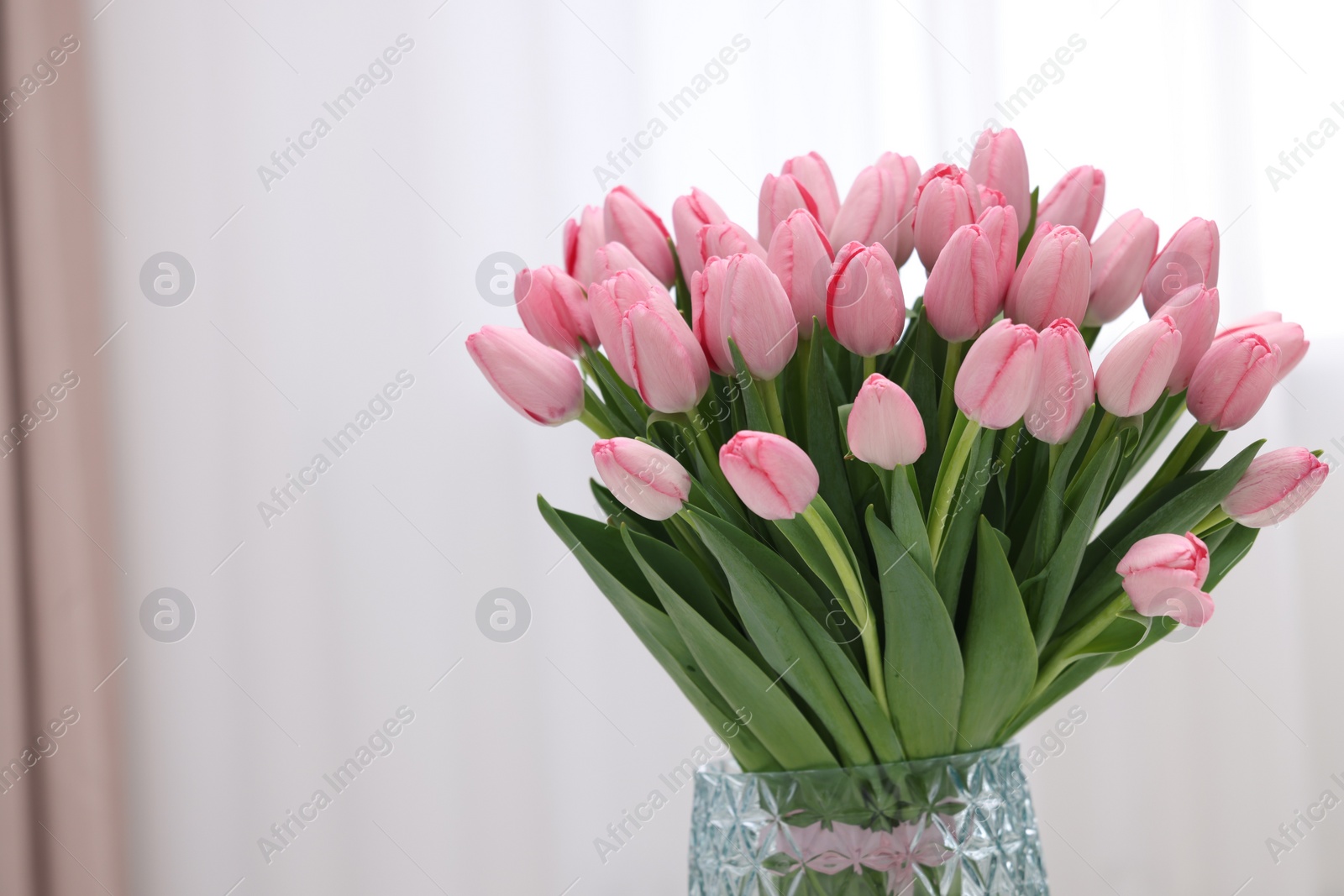 Photo of Bouquet of beautiful pink tulips in vase indoors, space for text