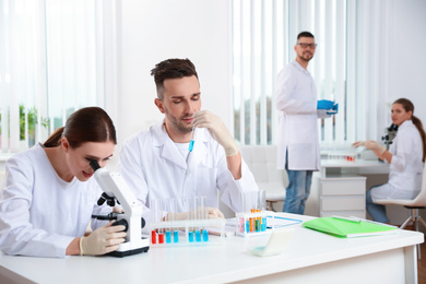Scientist with microscope and colleagues in laboratory. Medical research