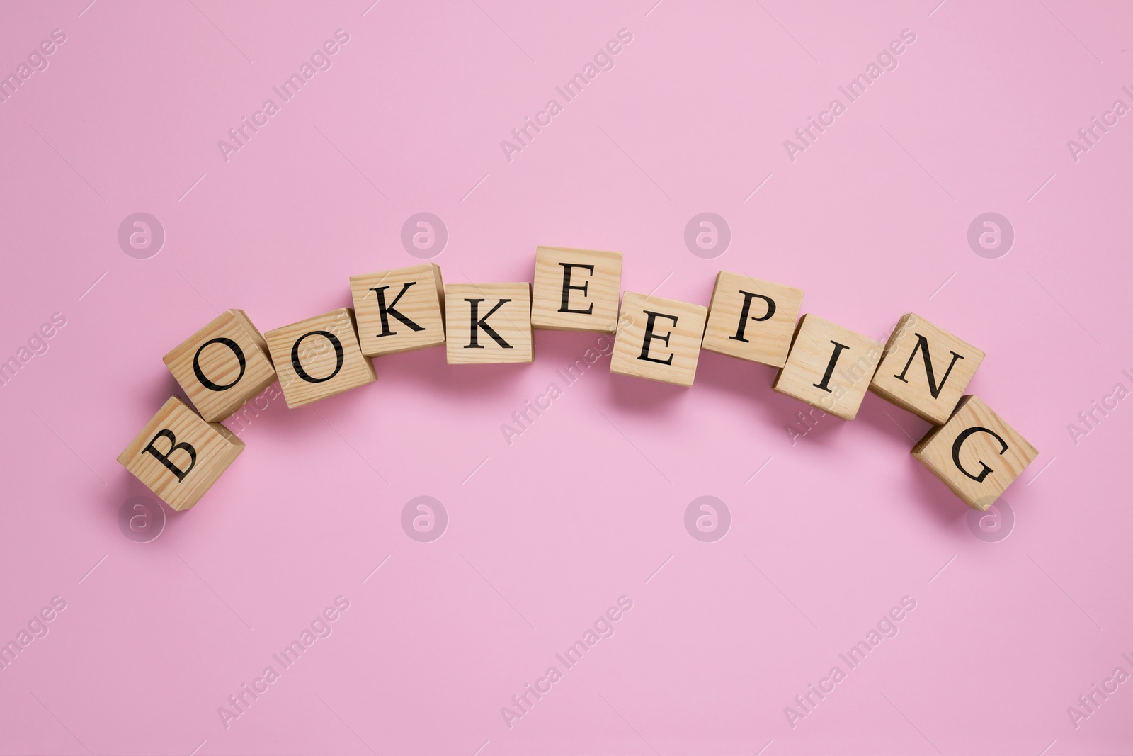 Photo of Word Bookkeeping made with wooden cubes on pink background, top view