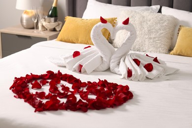 Photo of Honeymoon. Swans made with towels and beautiful heart of rose petals on bed