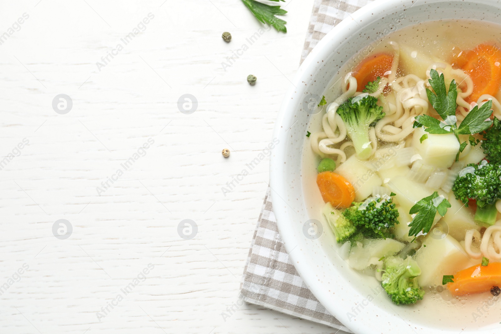 Photo of Bowl of fresh homemade vegetable soup on white wooden background, top view. Space for text