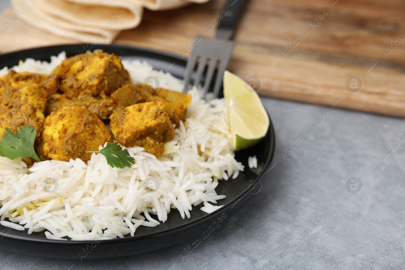 Photo of Delicious chicken curry with rice on grey table, closeup