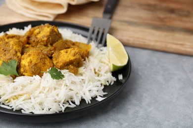 Photo of Delicious chicken curry with rice on grey table, closeup