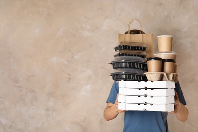 Photo of Courier with stack of orders on beige background, space for text. Food delivery service