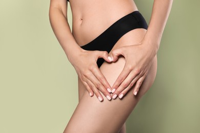 Closeup view of slim woman in underwear showing heart on light green background. Cellulite problem concept