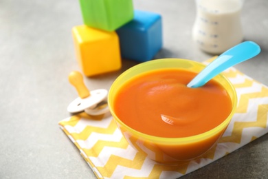 Photo of Bowl of healthy baby food on grey table. Space for text