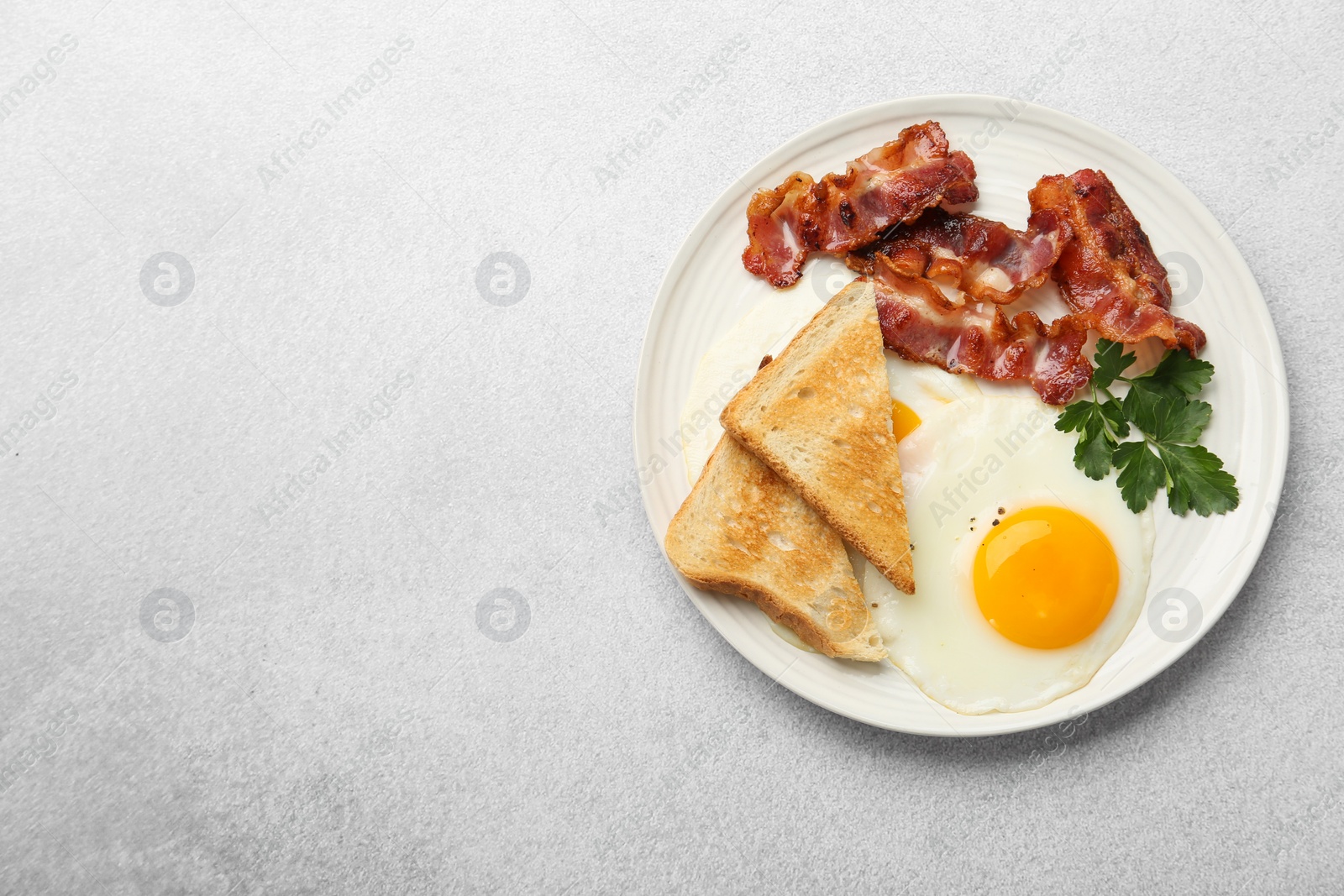 Photo of Delicious breakfast with sunny side up egg on light table, top view. Space for text