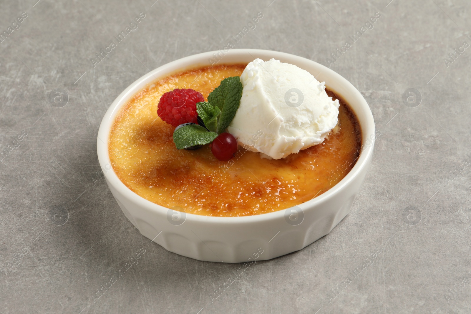 Photo of Delicious creme brulee with scoop of ice cream, fresh berries and mint on light grey table