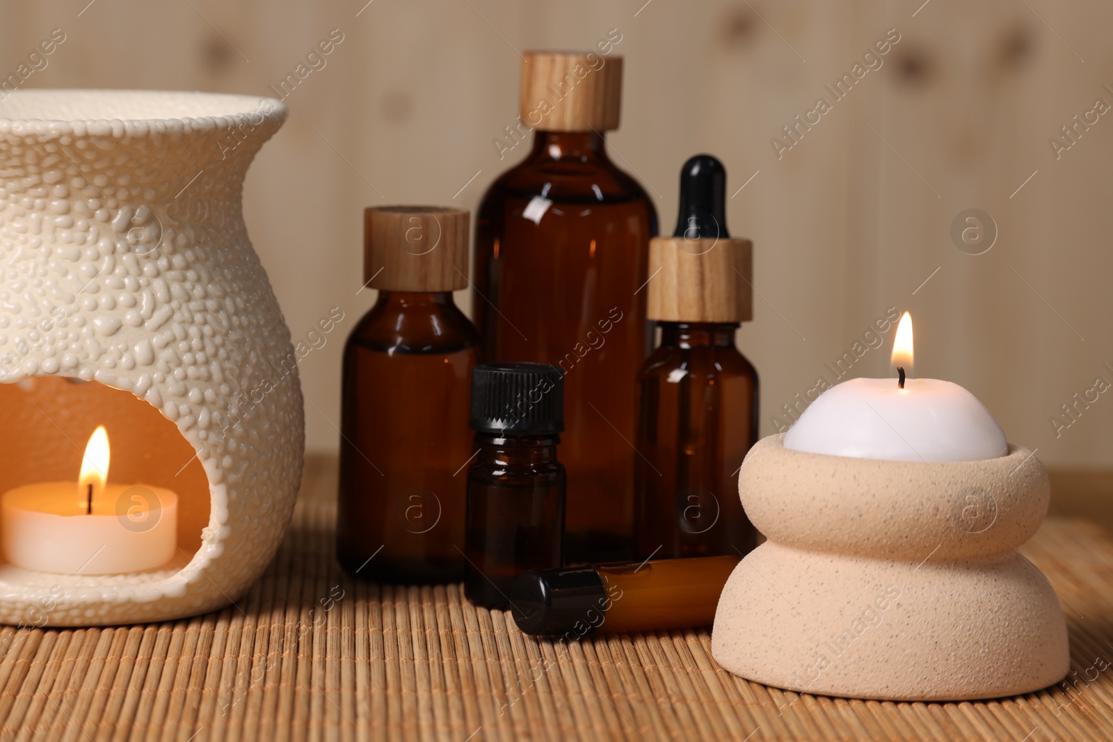 Photo of Different aromatherapy products and burning candles on table, closeup