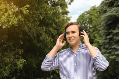 Photo of Handsome young man with headphones outdoors on sunny day