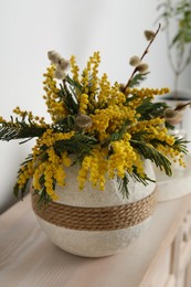 Beautiful mimosa flowers in vase on wooden table