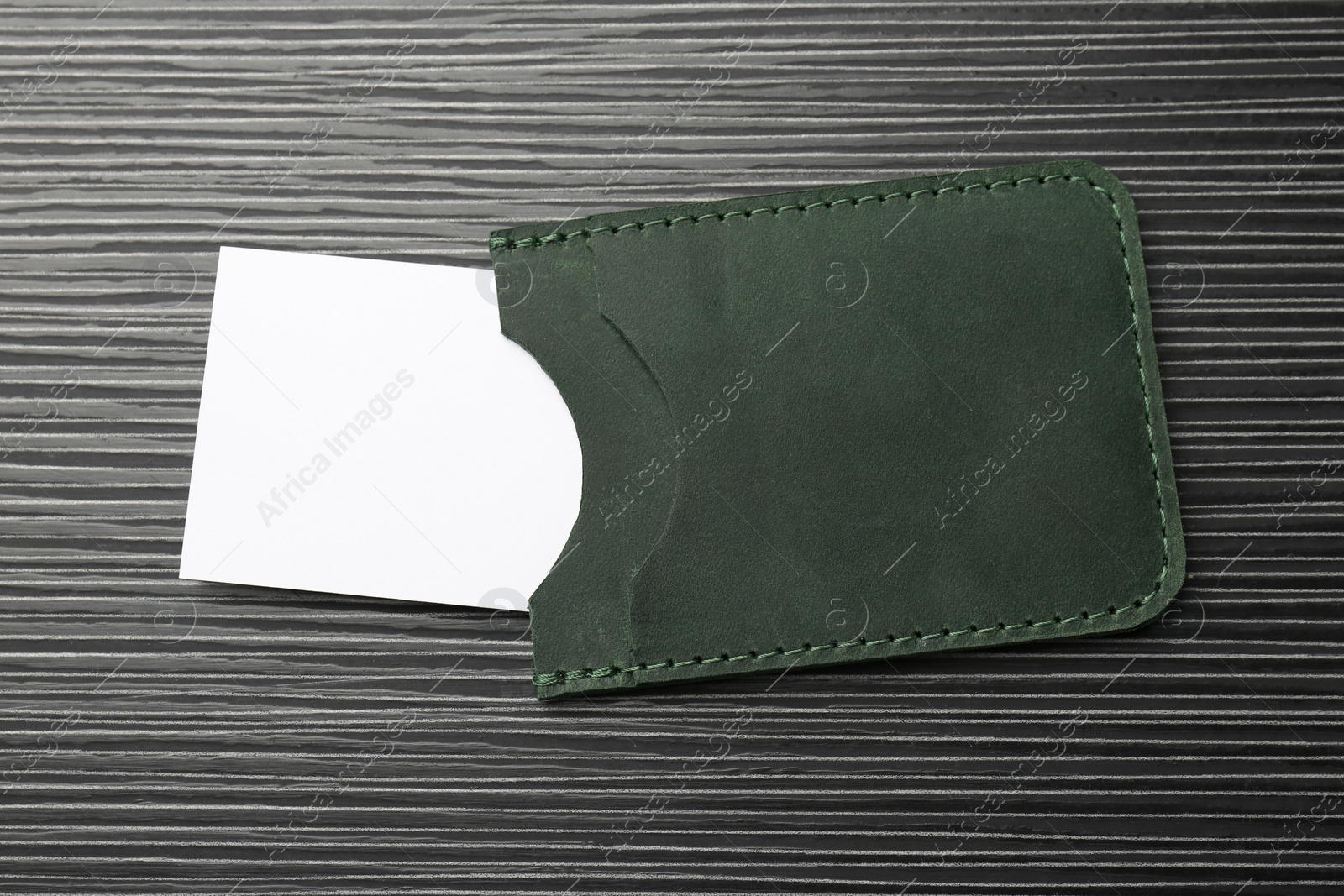 Photo of Leather business card holder with card on grey table, top view