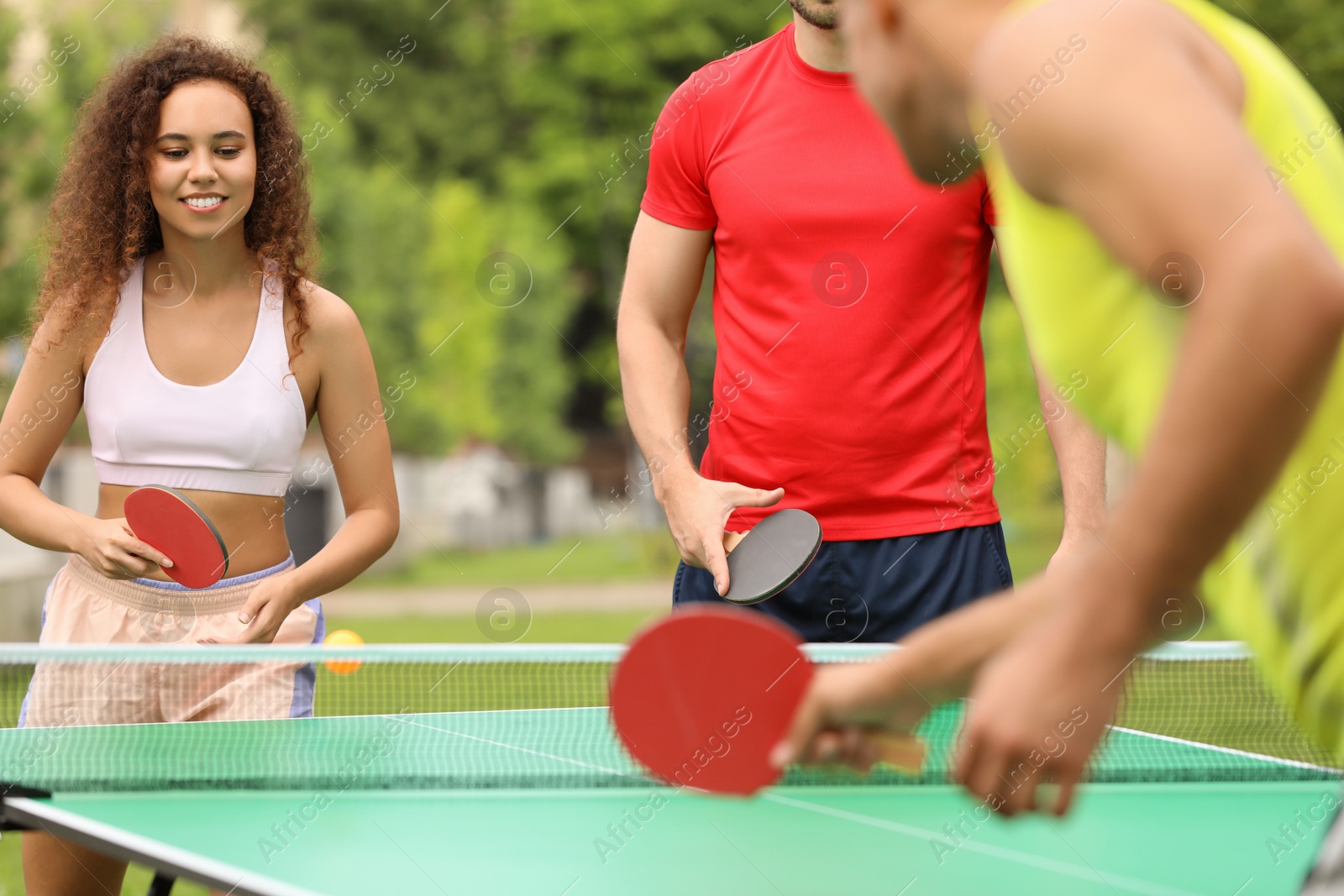 Photo of Friends playing ping pong outdoors on summer day