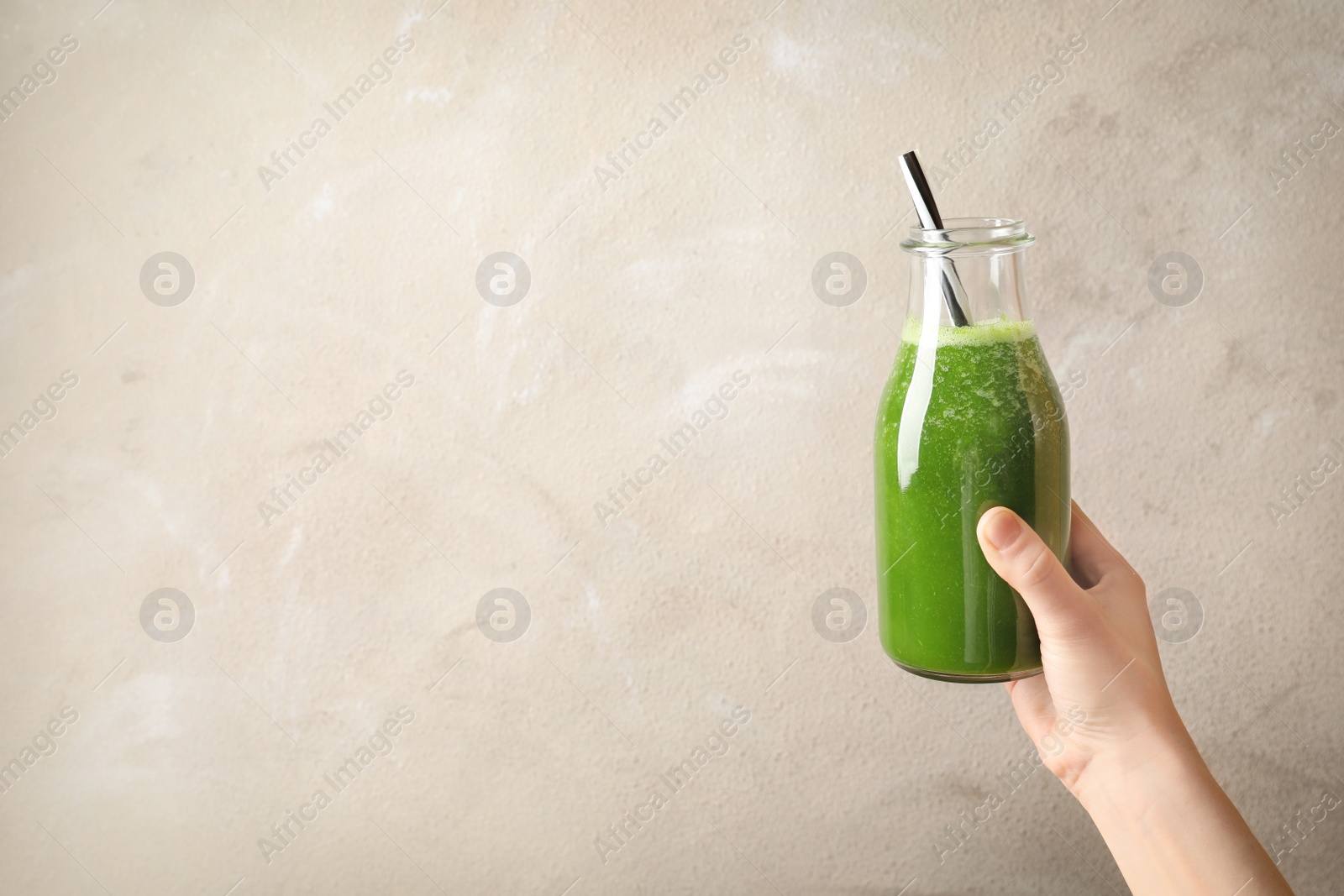 Photo of Woman holding bottle with delicious detox juice on light background