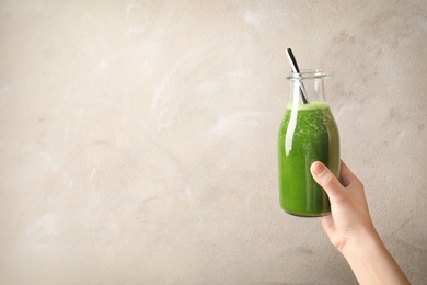 Woman holding bottle with delicious detox juice on light background