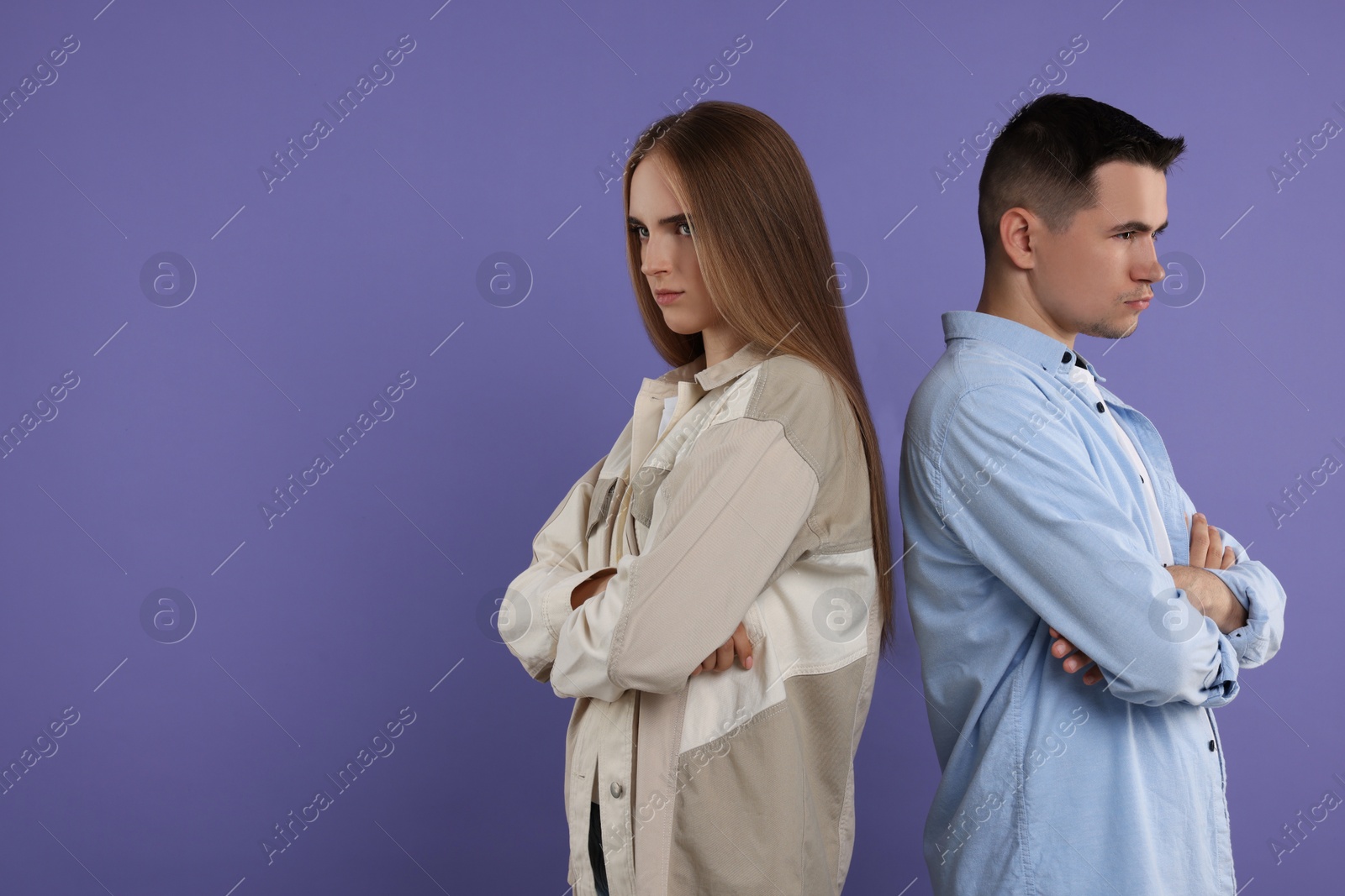 Photo of Portrait of resentful couple with crossed arms on violet background, space for text