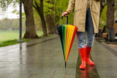 Young woman with umbrella walking in park on spring day, closeup. Space for text