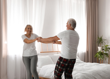 Photo of Happy mature couple dancing together in bedroom