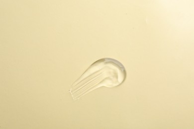 Photo of Smear of transparent ointment on beige background, top view