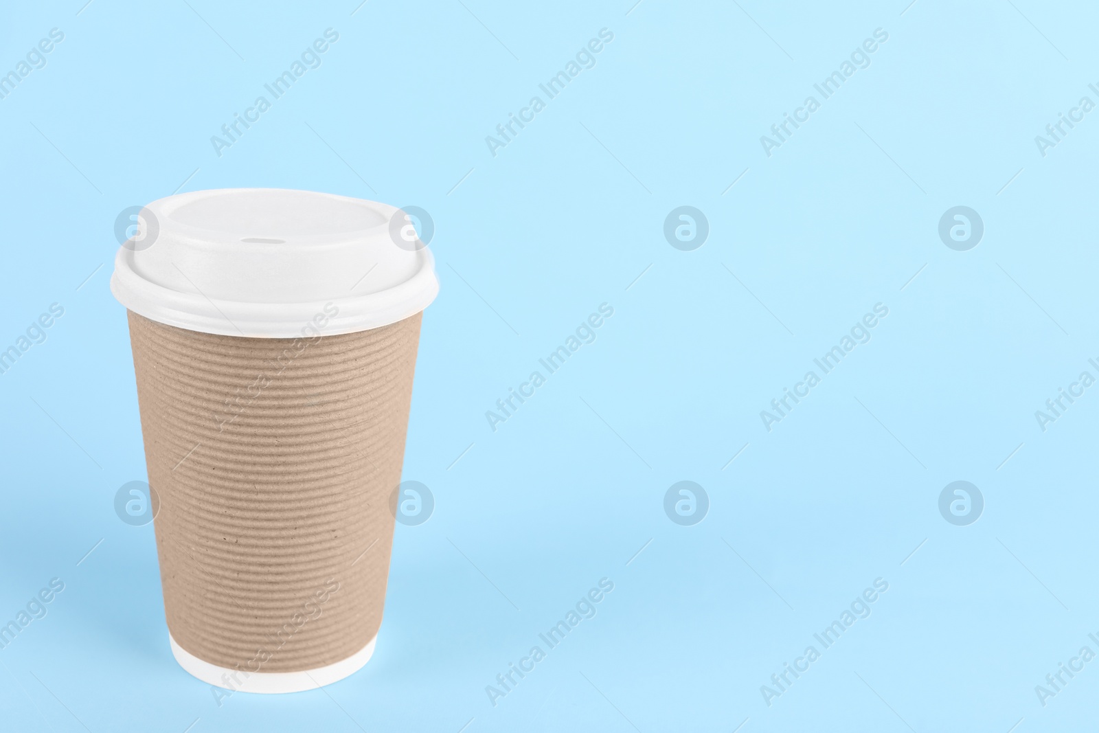 Photo of Paper cup with plastic lid on light blue background, space for text. Coffee to go