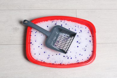 Photo of Cat tray with crystal litter and scoop on wooden floor, top view