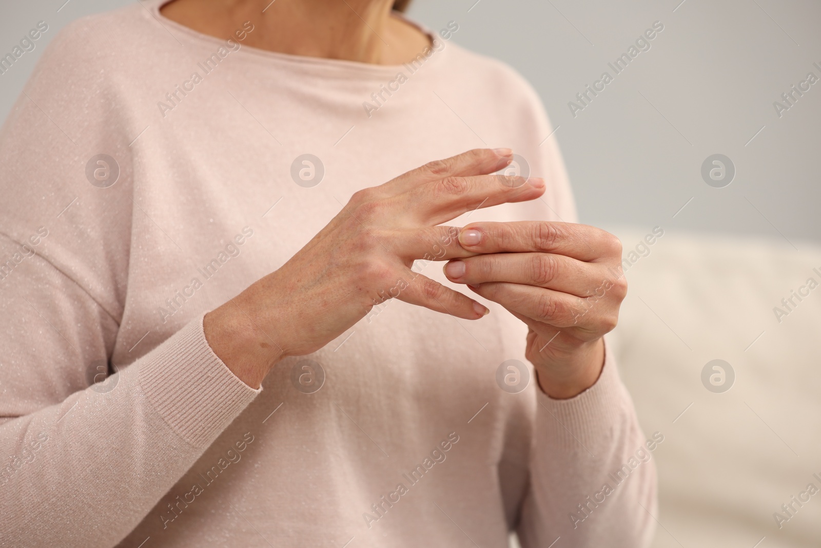 Photo of Mature woman suffering from pain in hand indoors, closeup. Rheumatism symptom