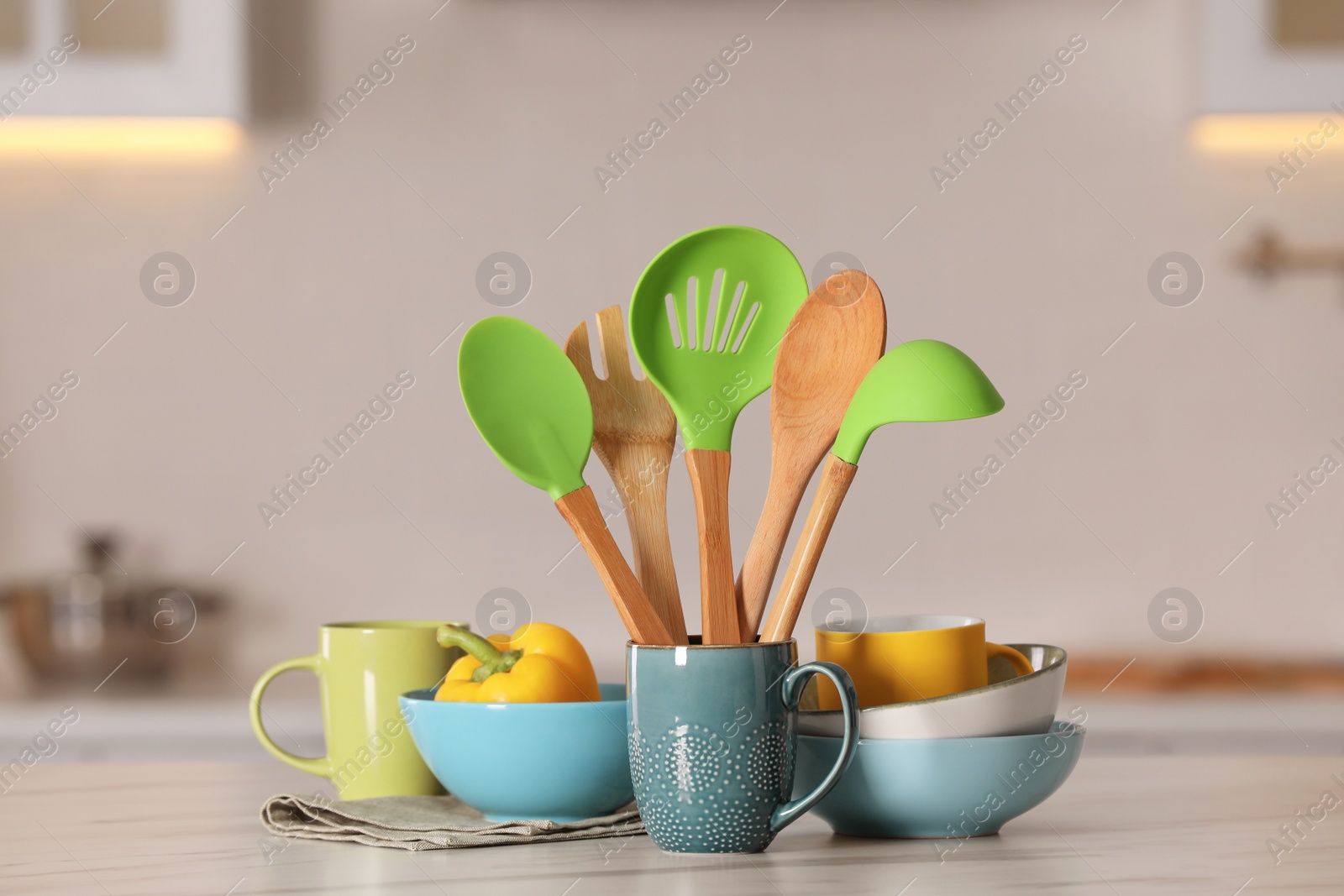 Photo of Set of different cooking utensils and ceramic dishes on white table in kitchen