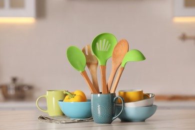 Set of different cooking utensils and ceramic dishes on white table in kitchen