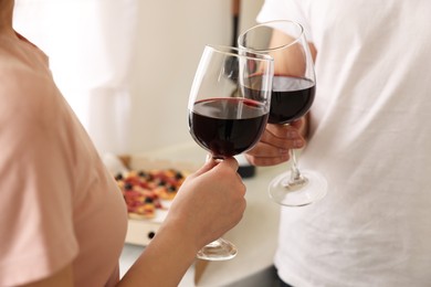 Photo of Couple clinking glasses of wine at home, closeup