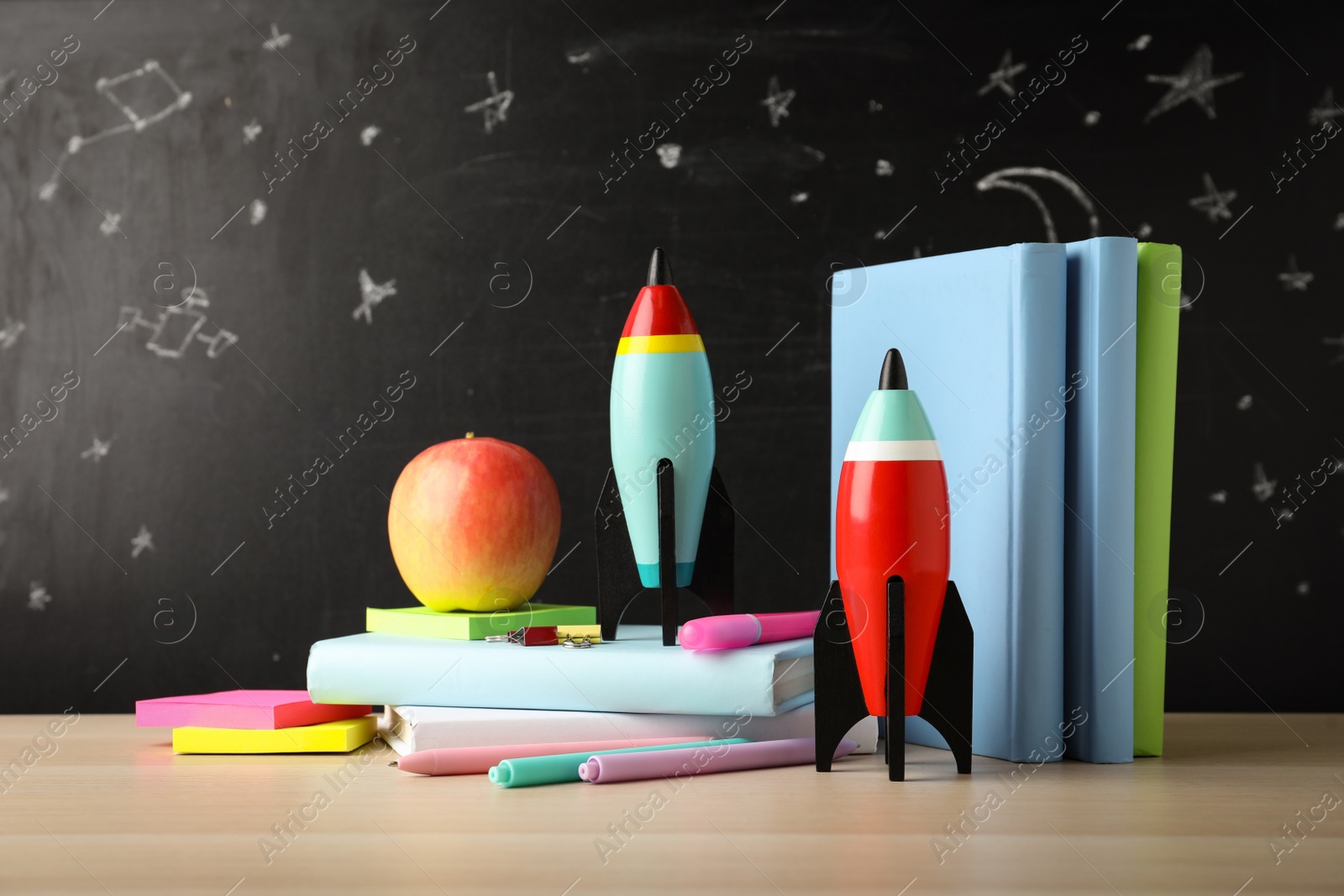 Photo of Bright toy rockets and school supplies on wooden table