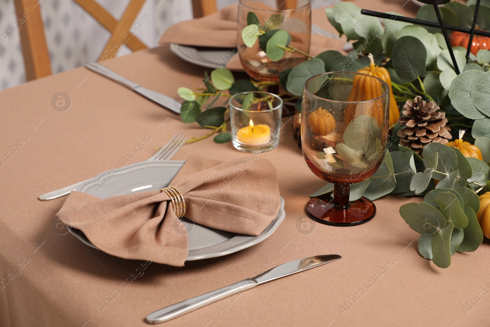 Photo of Autumn table setting with eucalyptus branches and pumpkins indoors