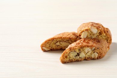 Photo of Traditional Italian almond biscuits (Cantucci) on white wooden table, space for text