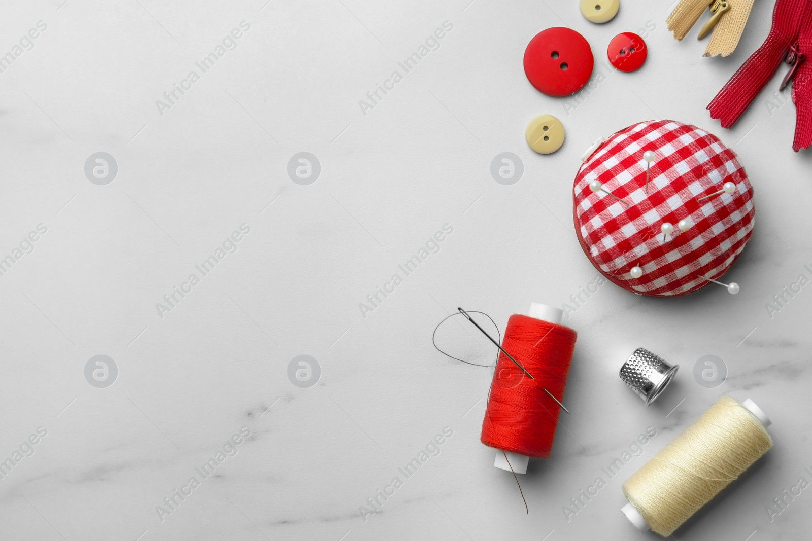 Photo of Threads and other sewing supplies on white marble table, flat lay. Space for text