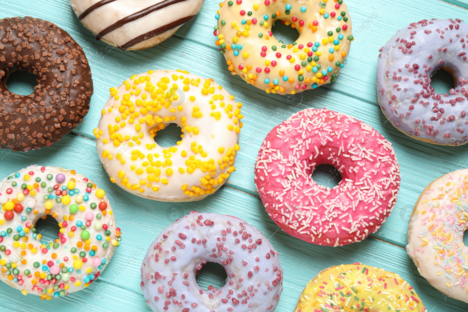 Photo of Delicious glazed donuts on blue wooden table, flat lay