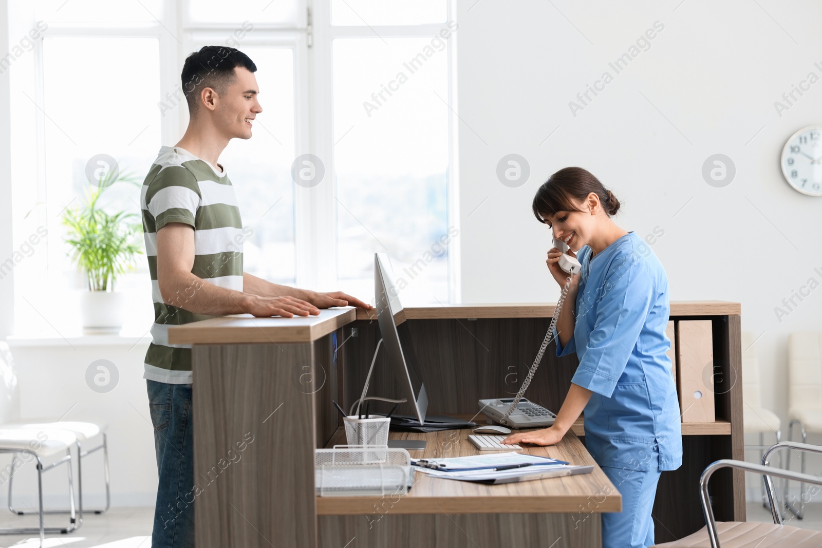 Photo of Smiling medical assistant working with patient at hospital reception