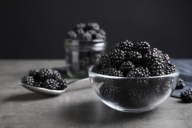 Delicious fresh ripe blackberries in glass bowl on grey table. Space for text