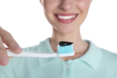 Photo of Woman holding brush with charcoal toothpaste on white background, closeup
