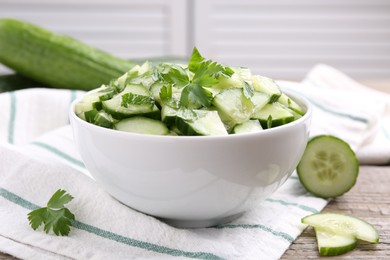 Delicious cucumber salad in bowl on wooden table