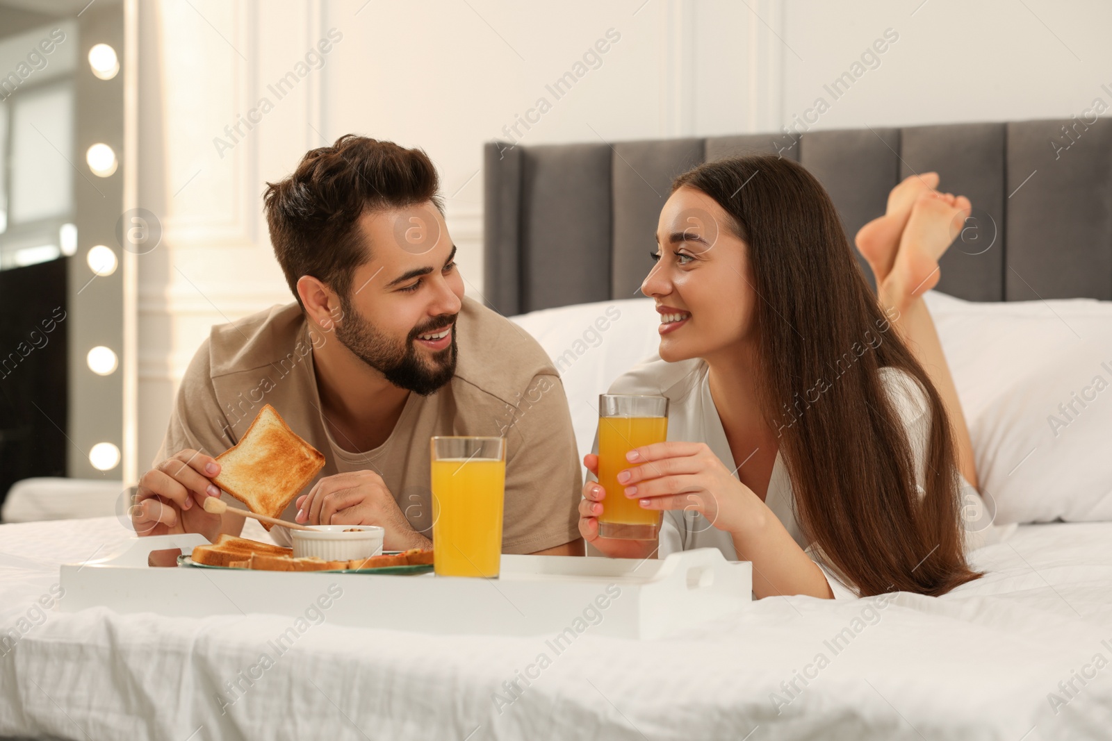 Photo of Happy couple having breakfast on bed at home