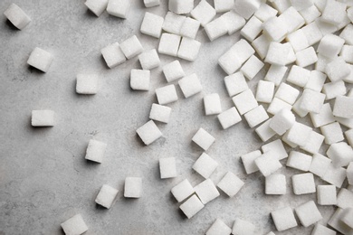Refined sugar cubes on grey background, top view