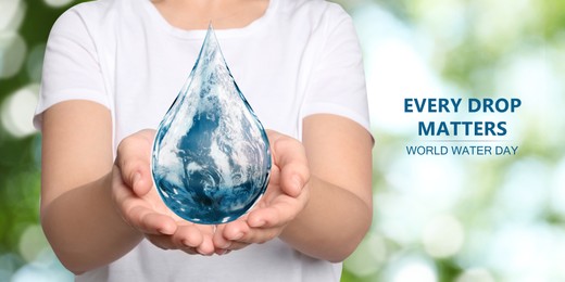 Image of World Water Day. Woman holding icon of drop with Earth image inside on blurred green background, closeup