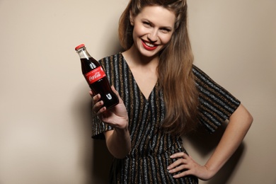 MYKOLAIV, UKRAINE - NOVEMBER 28, 2018: Young woman with bottle of Coca-Cola on color background