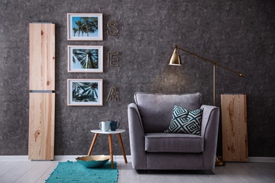 Photo of Interior of modern room with pictures on grey wall and cozy armchair