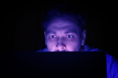 Internet addiction. Man with device at night. Toned in blue