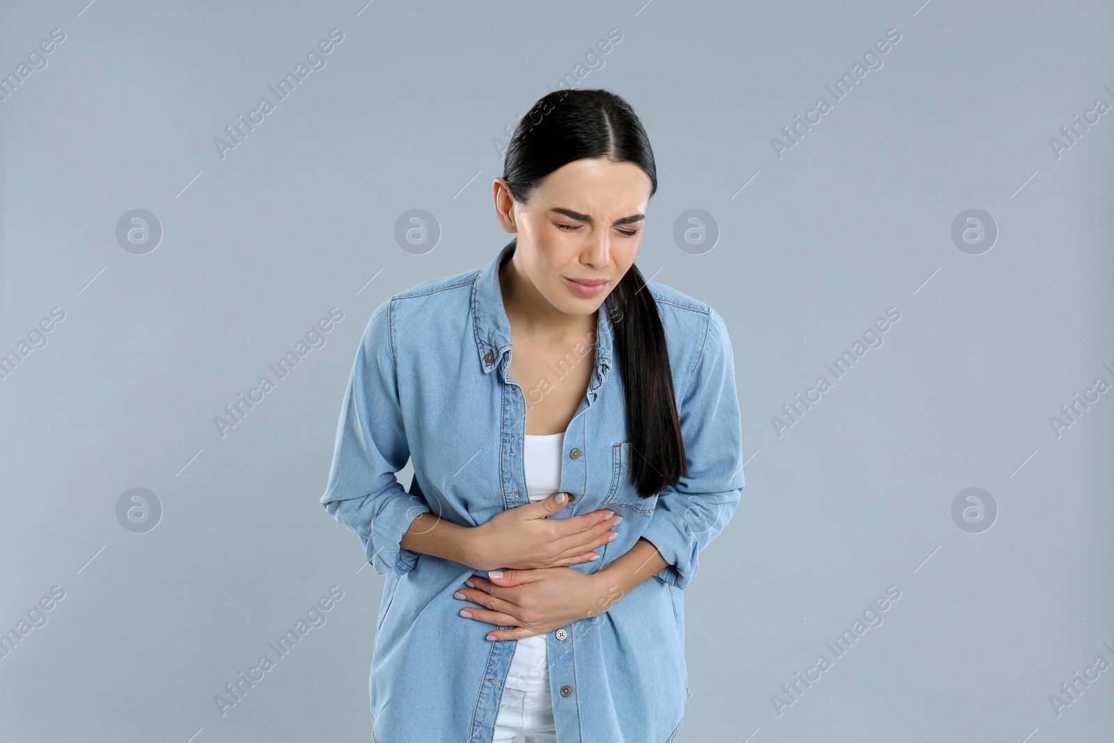 Photo of Woman suffering from stomach ache on grey background. Food poisoning