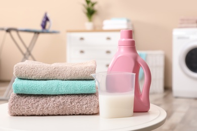Photo of Stack of towels and detergent on table against blurred background