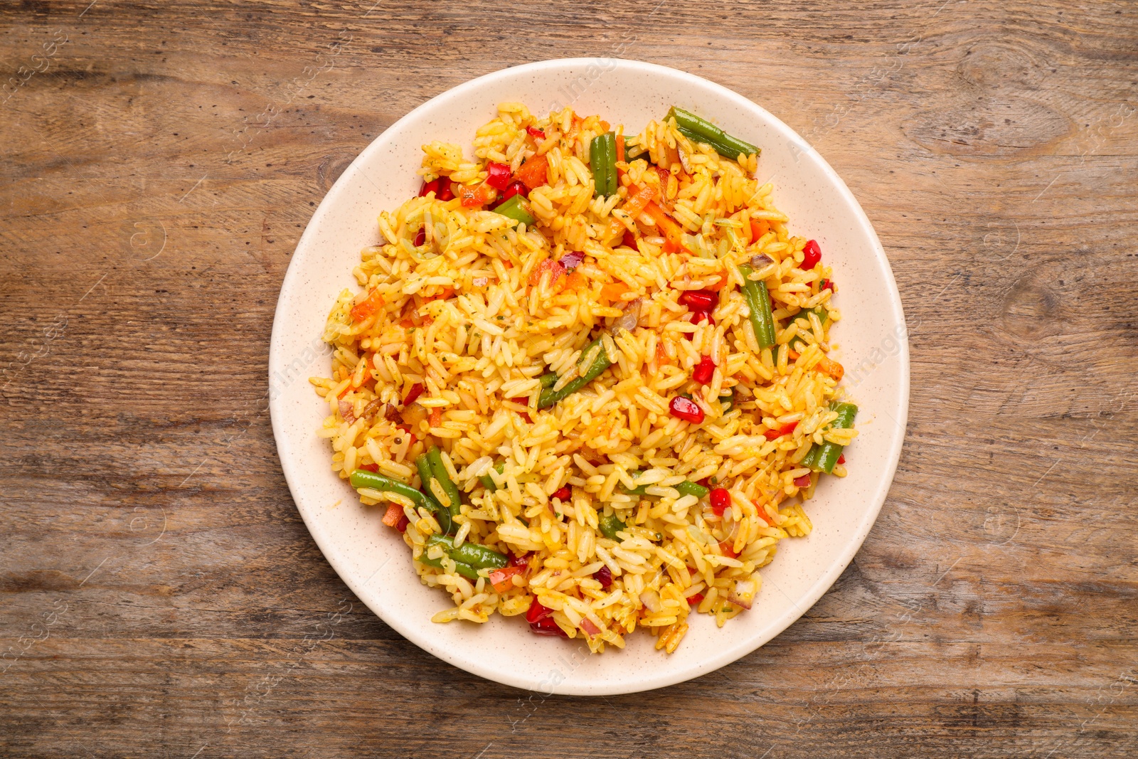 Photo of Tasty rice pilaf with vegetables on wooden table, top view