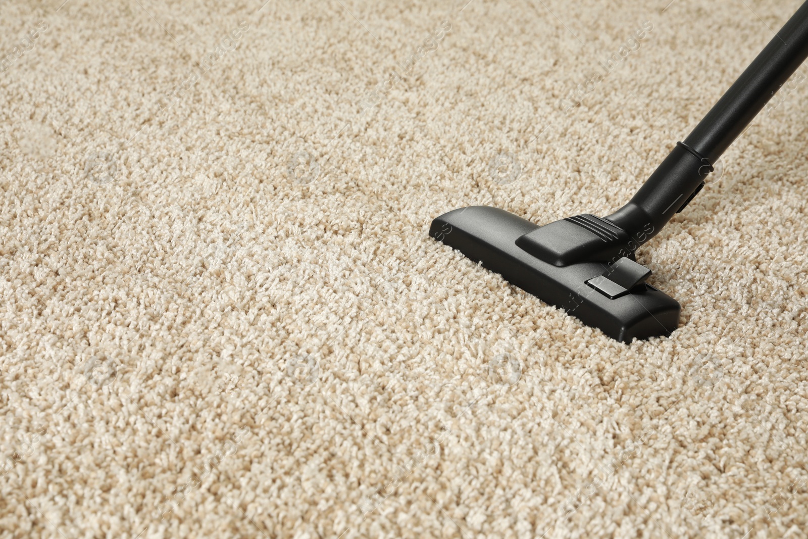 Photo of Removing dirt from beige carpet with modern vacuum cleaner. Space for text