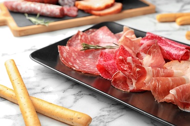 Cutting board with different meat delicacies on marble table